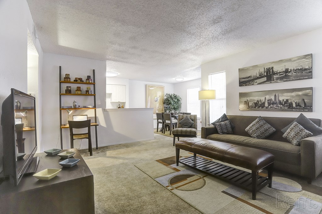 a living room with a couch and a coffee table and a kitchen with a counter