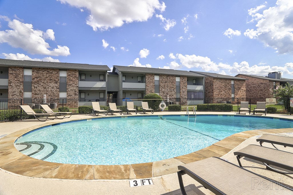 a swimming pool with lounge chairs in front of a building