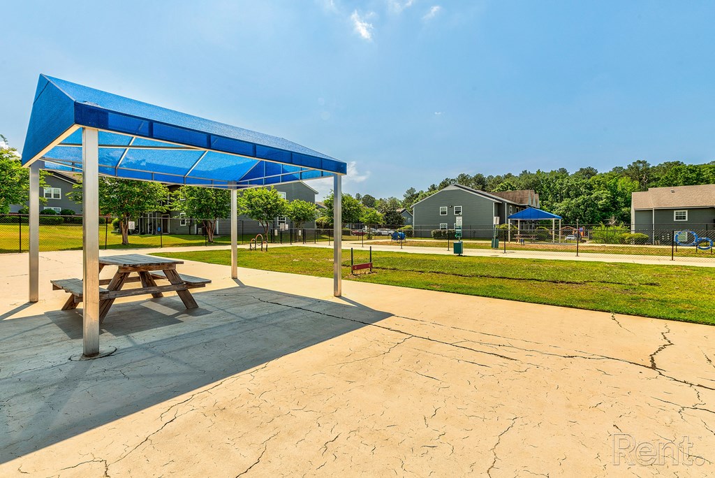 a picnic table sitting under a blue canopy in a park