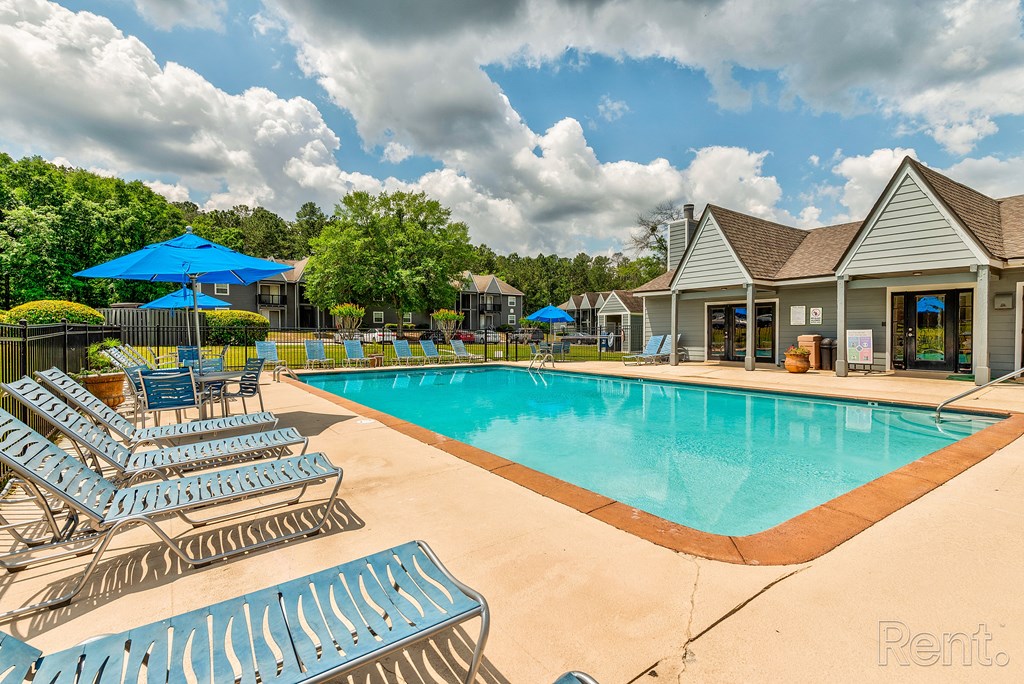 our resort style swimming pool is surrounded by lounge chairs and umbrellas