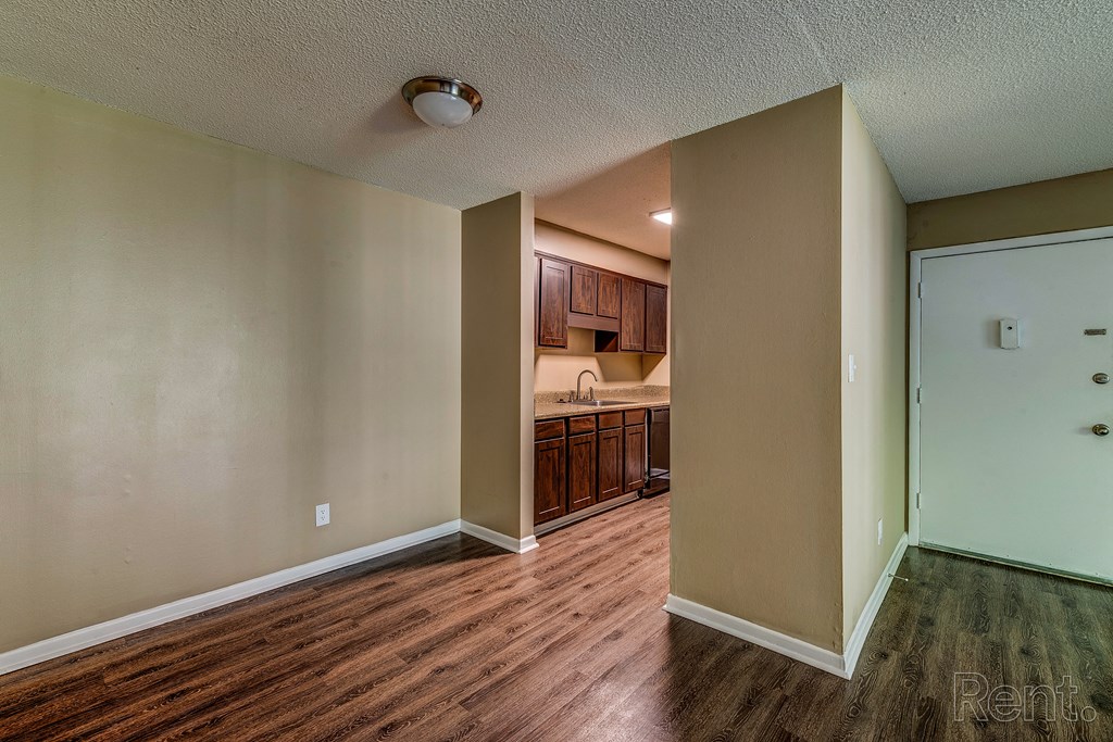 an empty living room and kitchen with wood flooring