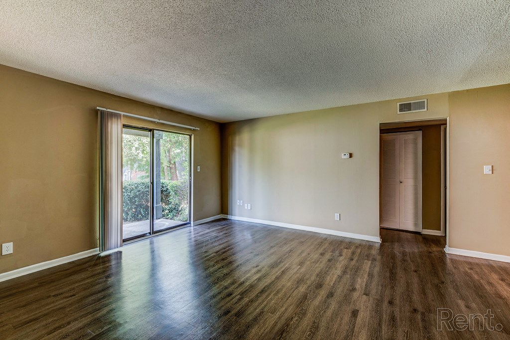 an empty living room with wood floors and a sliding glass door