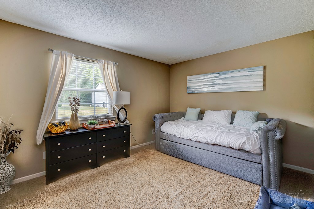 a bedroom with a bed and a dresser and a window