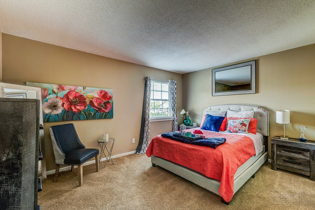 a bedroom with a bed and a chair and a window