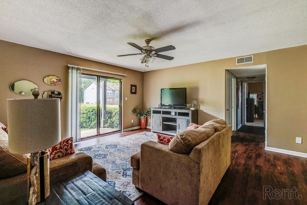 a living room with couches and a tv and a ceiling fan