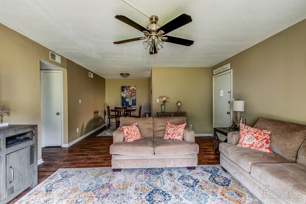 a living room with couches and a rug and a ceiling fan