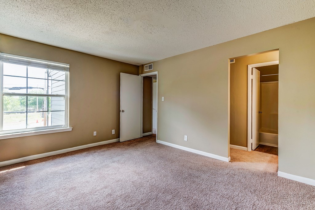 an empty living room with a large window and carpet