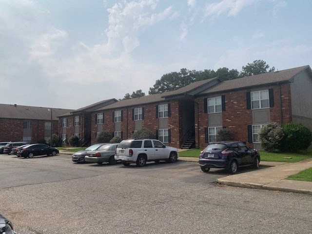 a parking lot in front of a brick apartment building