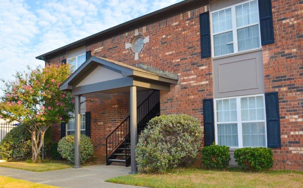 A brick house with a black door and a small porch.