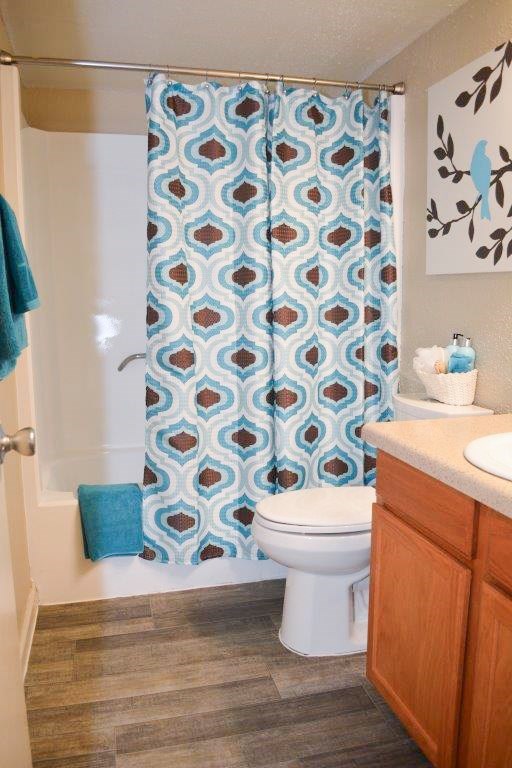 A blue and white shower curtain with a diamond pattern hangs over a white toilet in a bathroom.