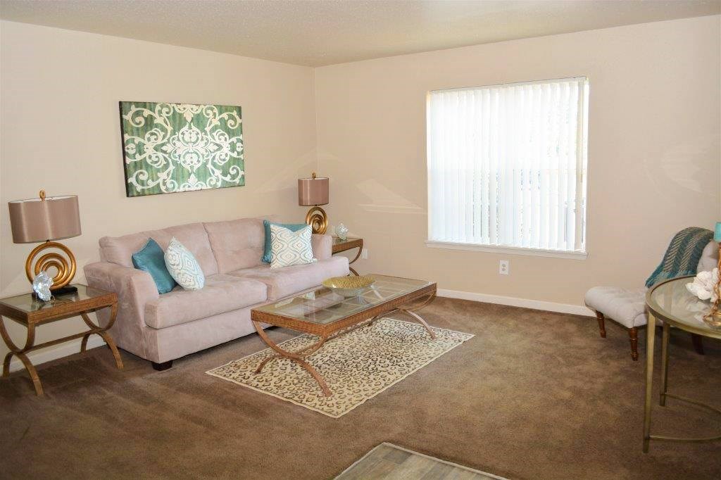 A living room with a couch, coffee table, and a painting on the wall.