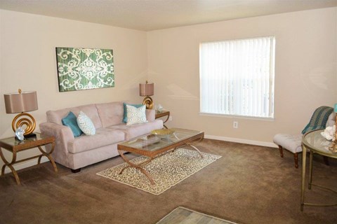A living room with a couch, coffee table, and a painting on the wall.