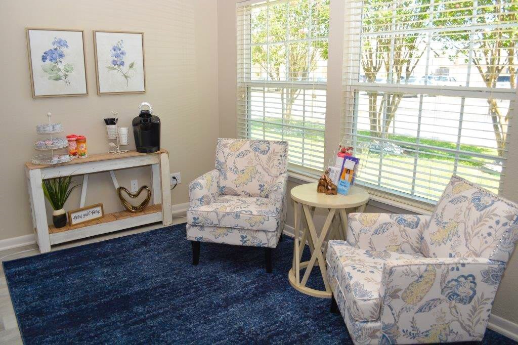 A room with two chairs and a table with a vase on it.