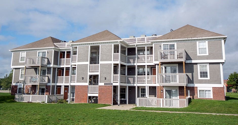 a large apartment building with balconies and a lawn