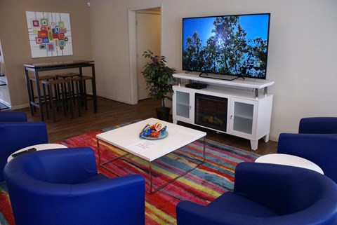 a living room with blue chairs and a television