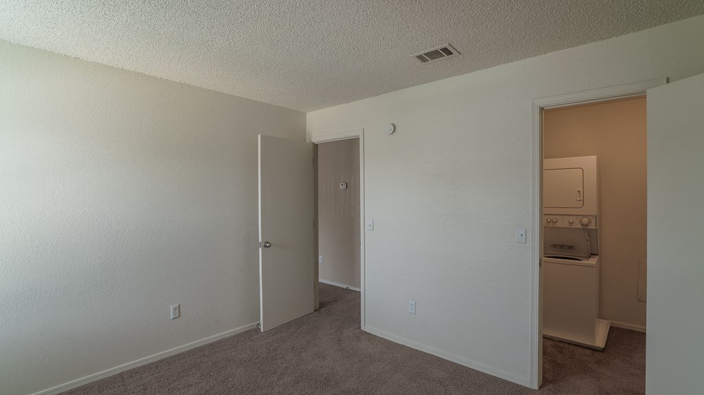an empty room with a door to a bathroom and a closet