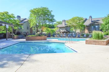 A swimming pool surrounded by a brick wall and trees.