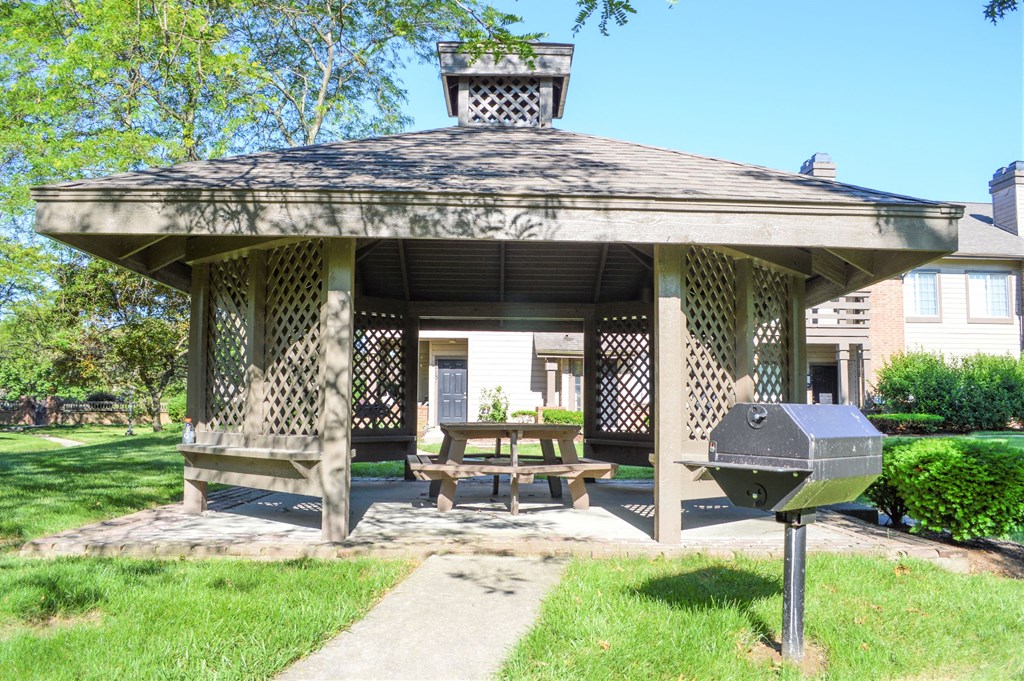 a gazebo with a picnic table and a grill
