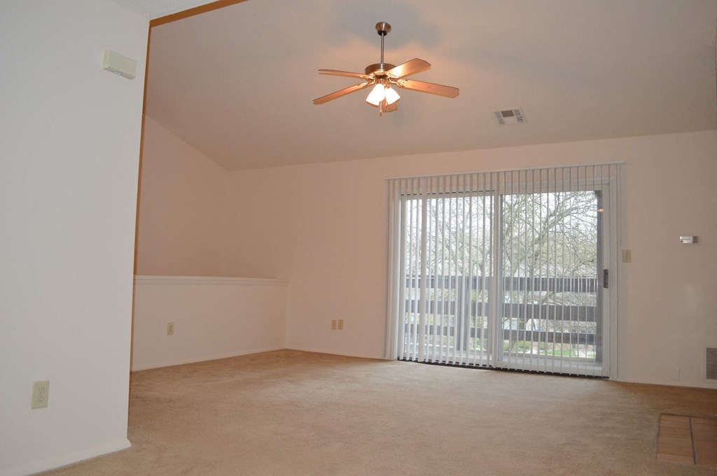 a living room with a large window and a ceiling fan