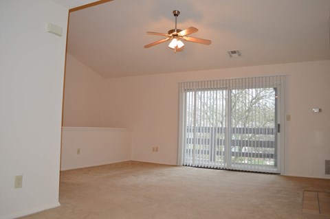 a living room with a large window and a ceiling fan