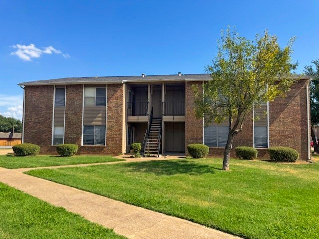 A brick apartment building with a tree in front.