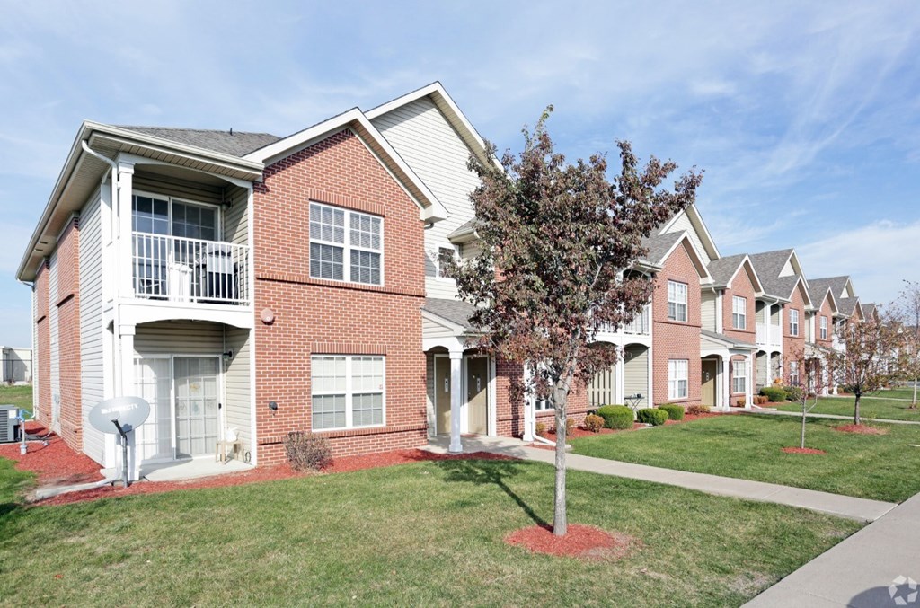 A red brick house with a tree in front.