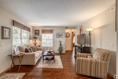 A living room with a striped chair and a couch.