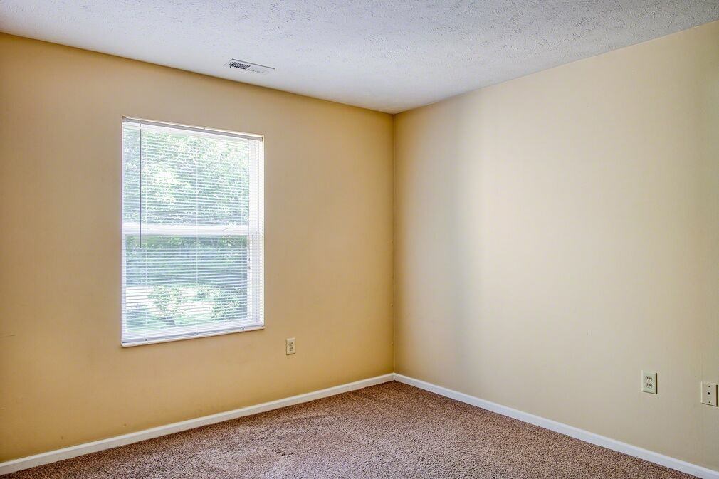 A room with a window and carpeted floor.