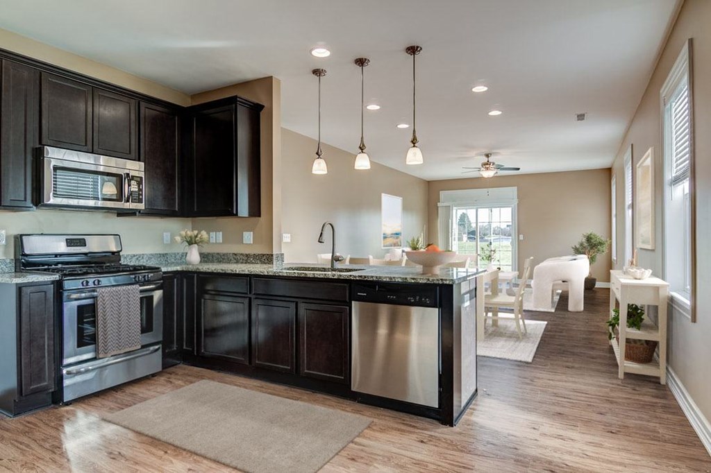A modern kitchen with dark wood cabinets and stainless steel appliances.