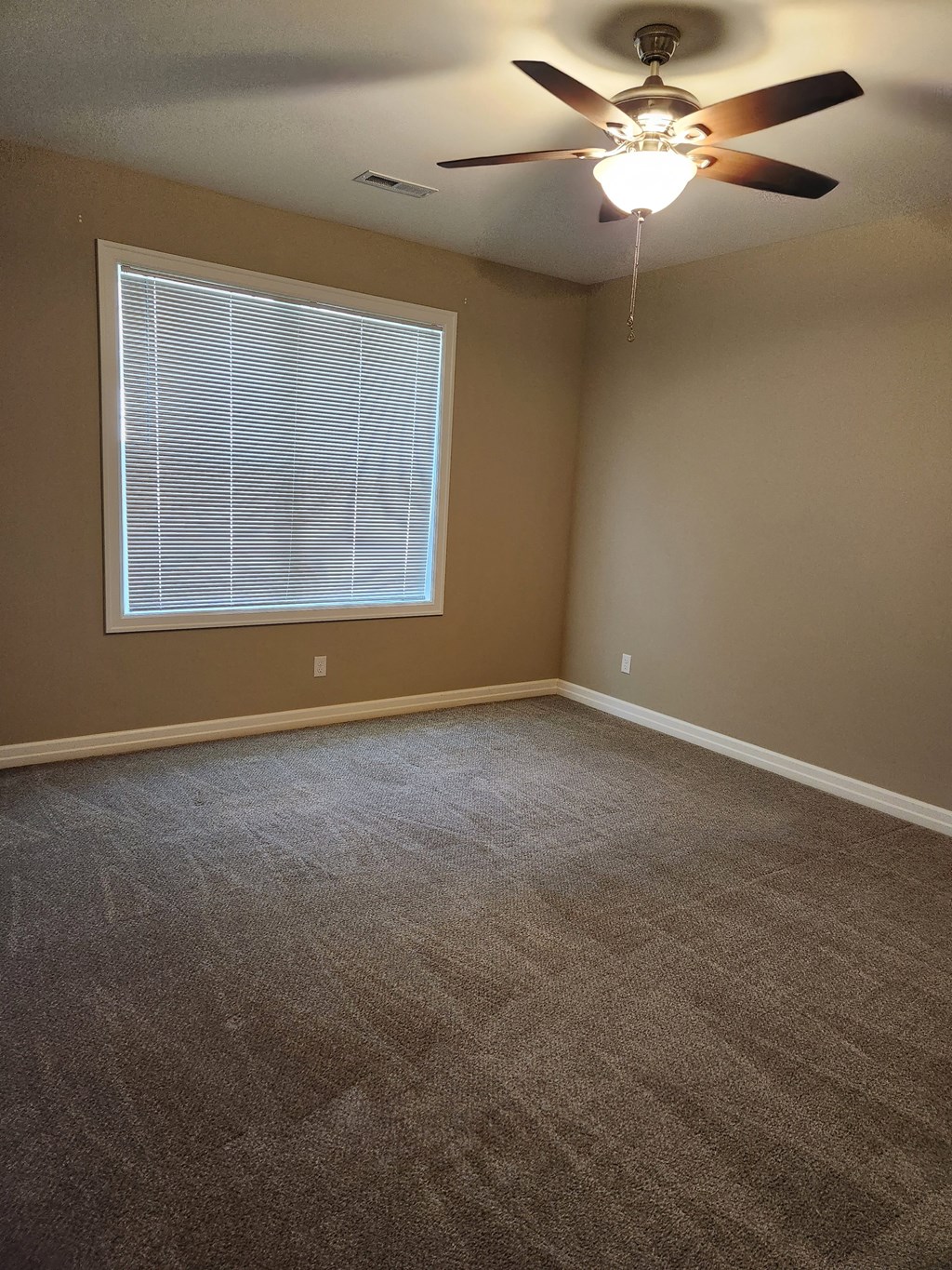 an empty living room with a ceiling fan and a window