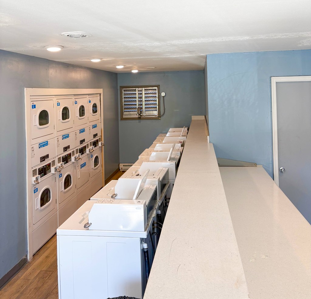 A laundry room with rows of washing machines.