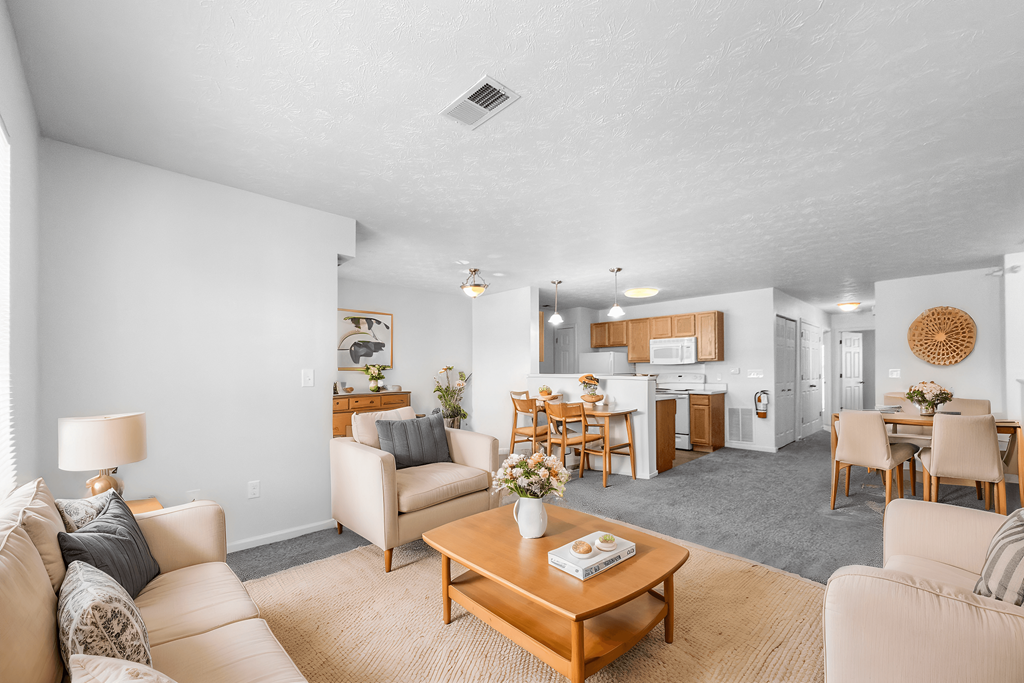 A well-lit, spacious living room with a variety of furniture and a dining area in the background.