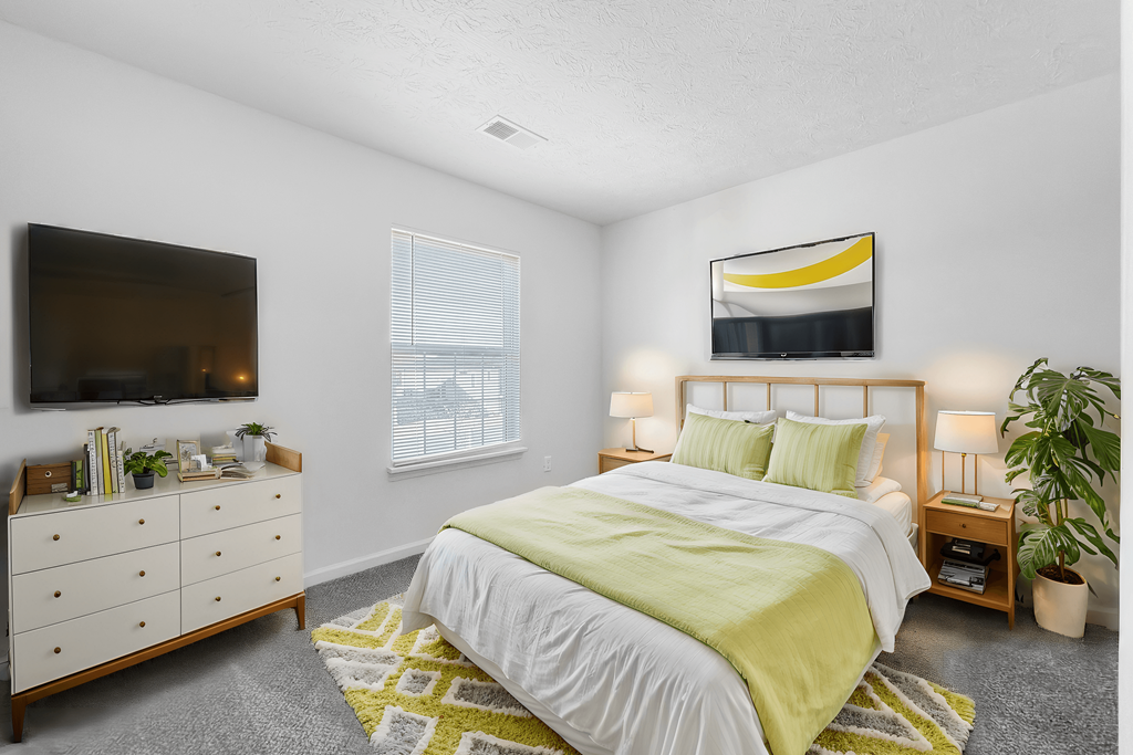 A bedroom with a bed, dresser, and a television.