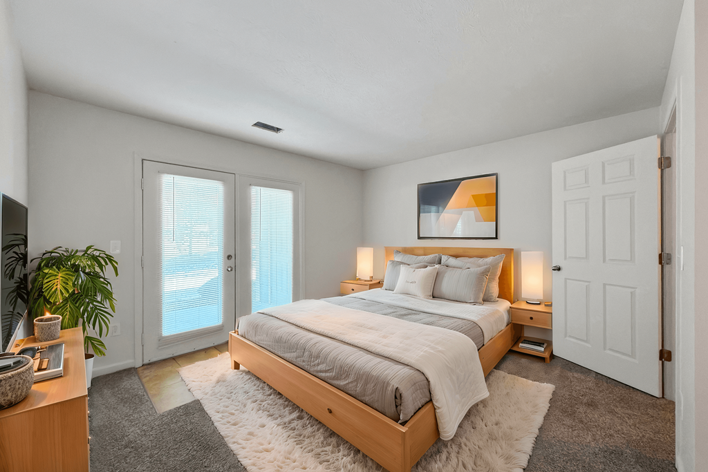 A bedroom with a large bed and a plant on the side table.