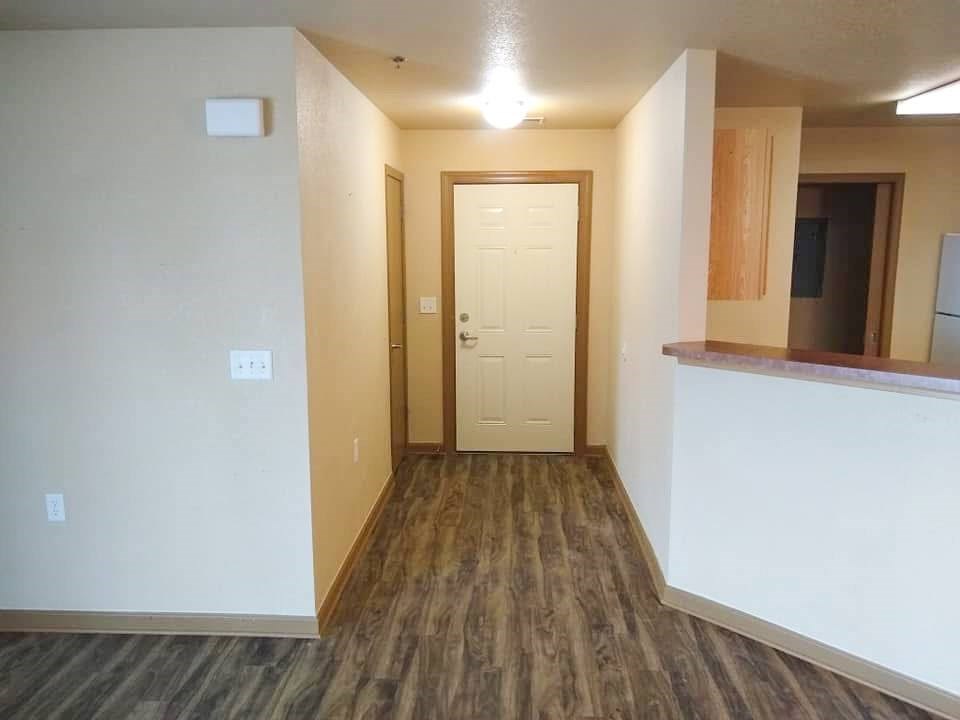 A hallway with a white door and wood flooring.