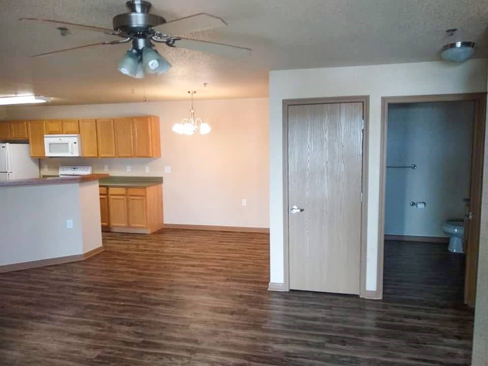 A room with a ceiling fan and wooden floors.