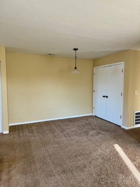 an empty living room with carpet and a white door