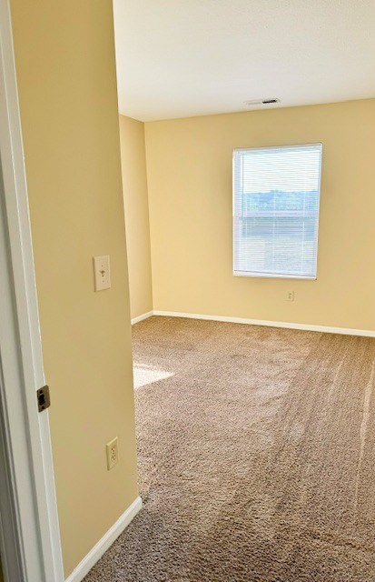 A room with a carpeted floor and a window.