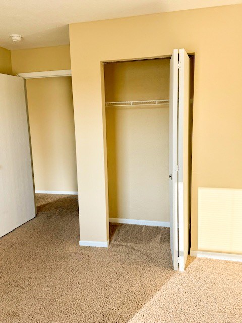 A white closet door is open in a room with tan walls.
