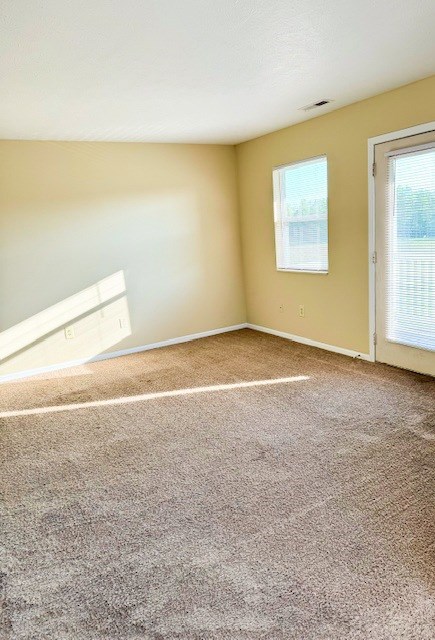 A room with a carpeted floor and a window with blinds.