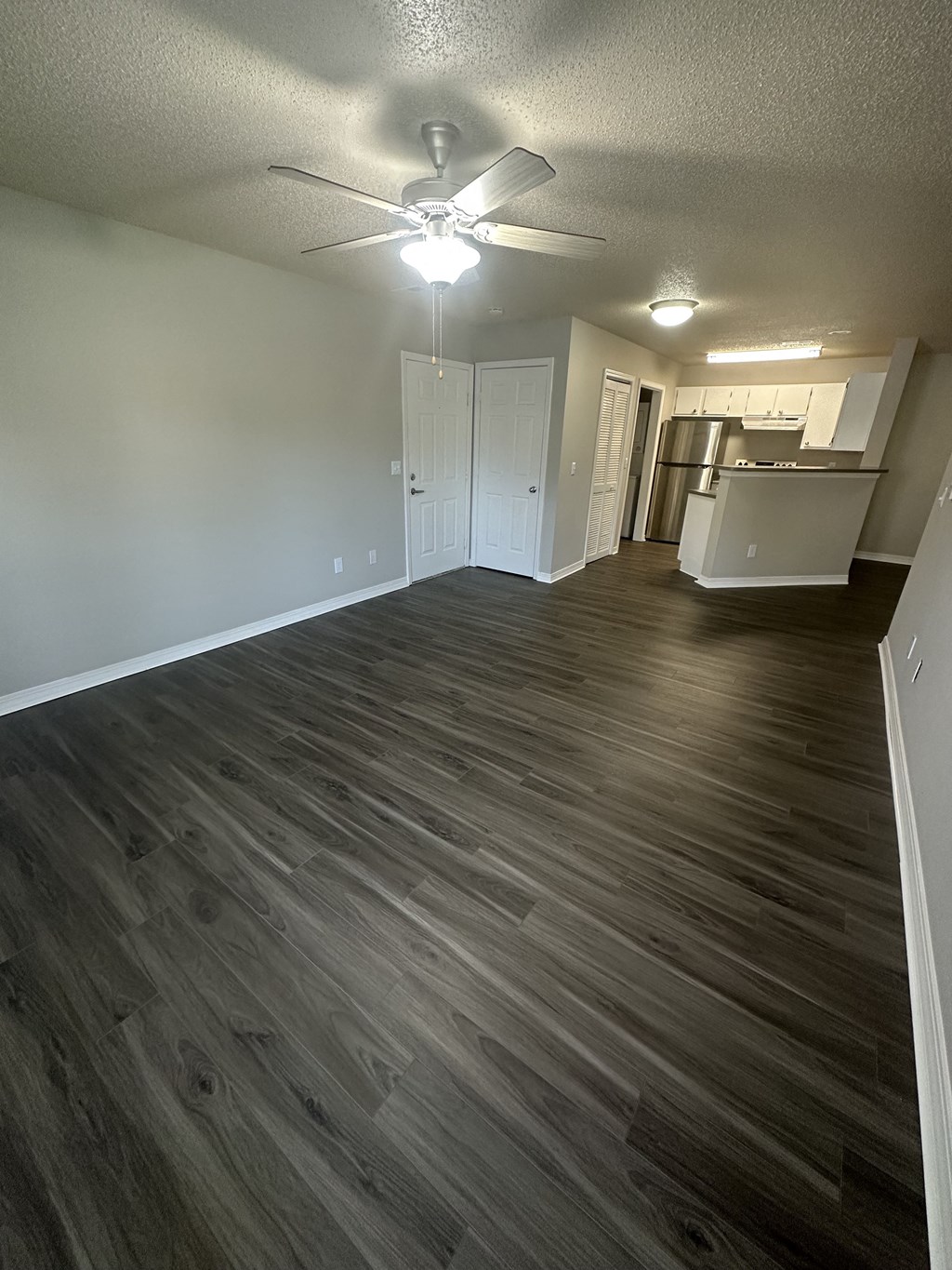 an empty living room with a ceiling fan