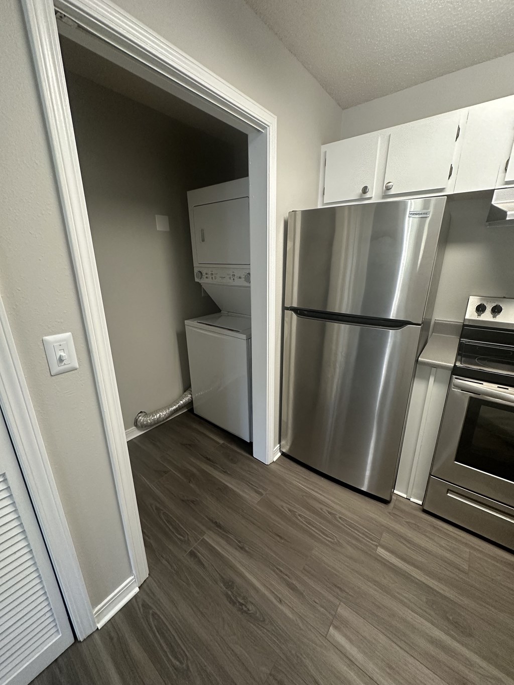 an empty kitchen with a stainless steel refrigerator and washer and dryer