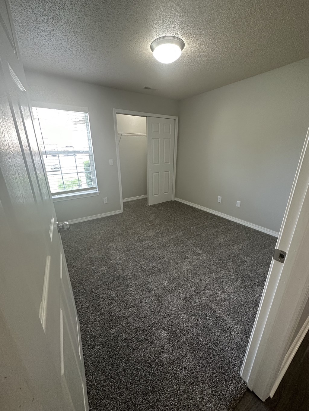 a bedroom with gray carpet and a window