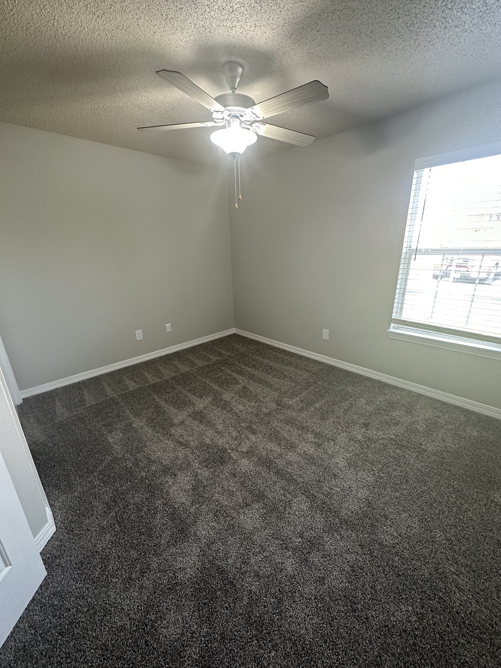 an empty room with a ceiling fan and a window