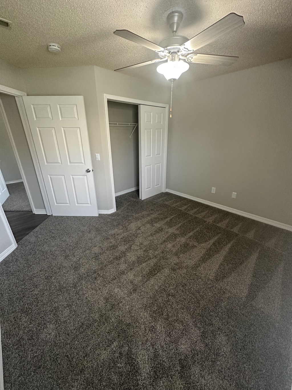 an empty room with a ceiling fan and a closet