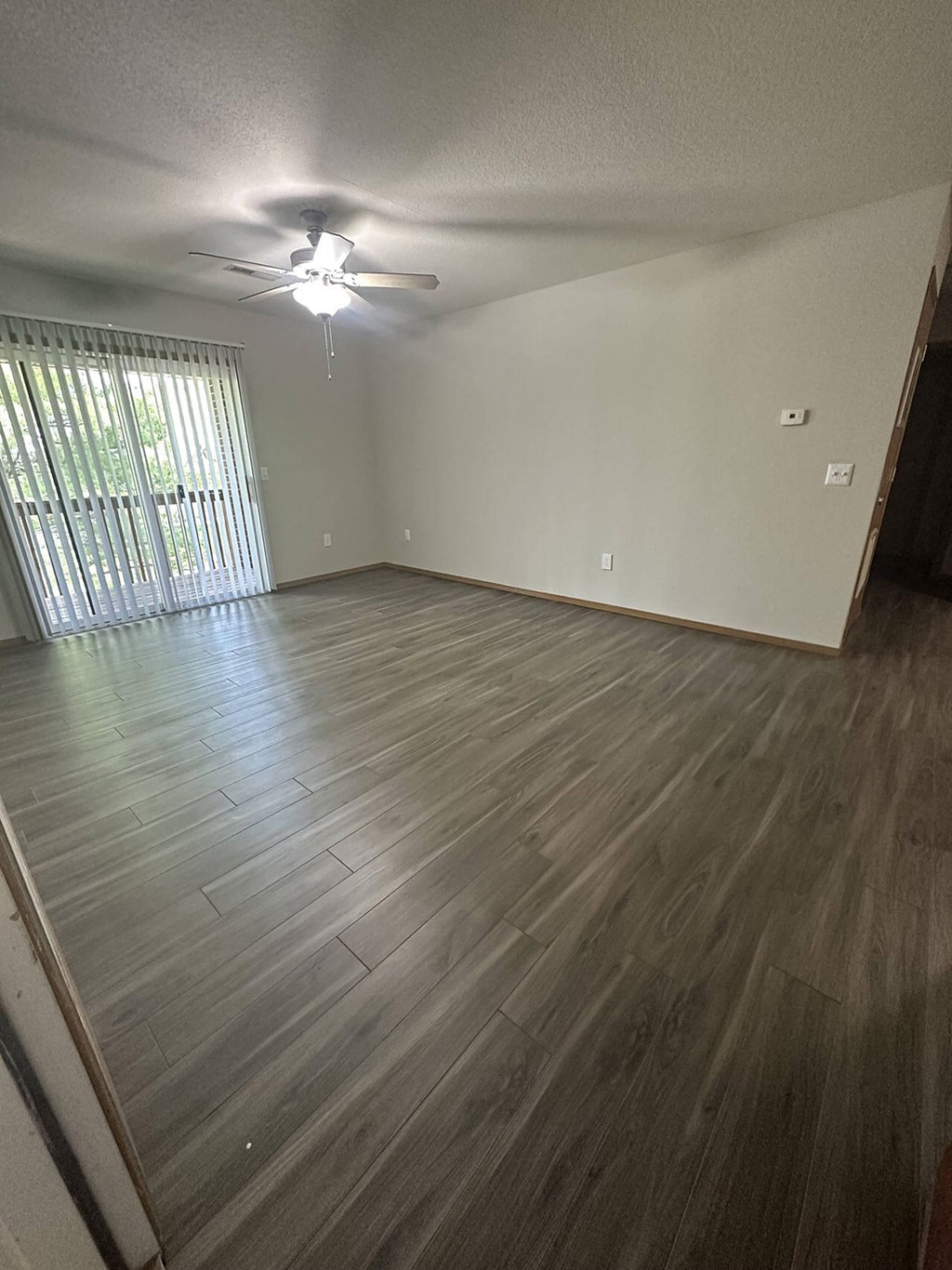 an empty living room with wood floors and a ceiling fan