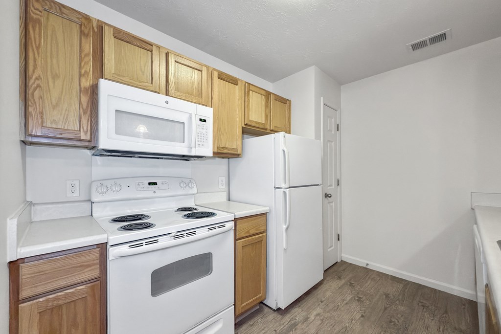 A kitchen with a white stove, white oven, and white microwave.