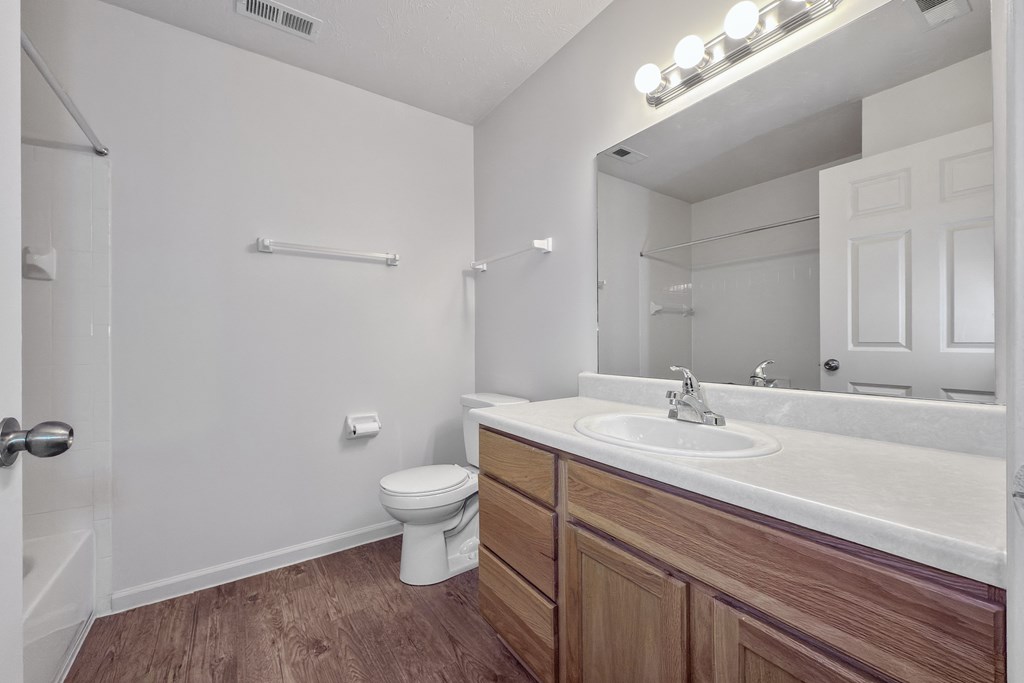 A white bathroom with a toilet, sink, and mirror.