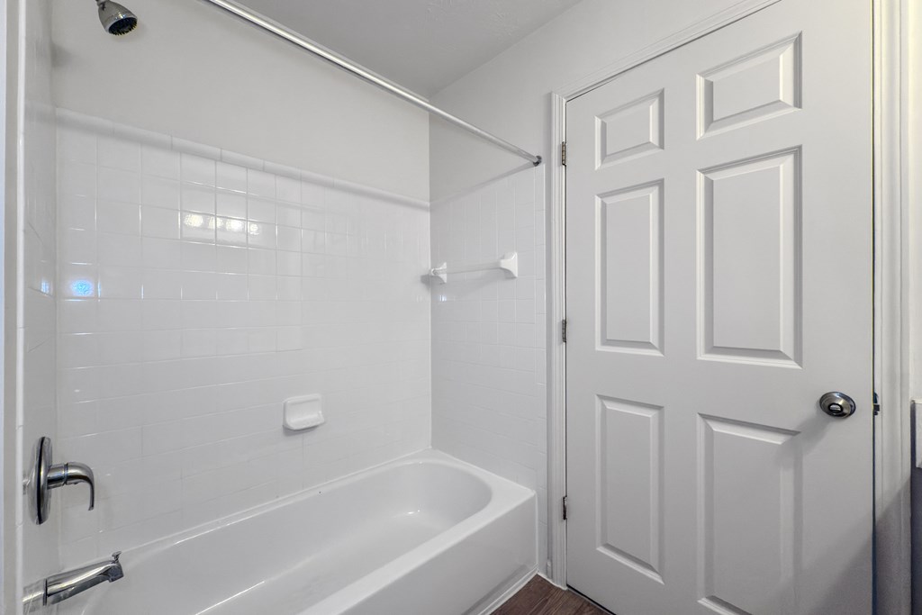 A white bathroom with a tub and a door.