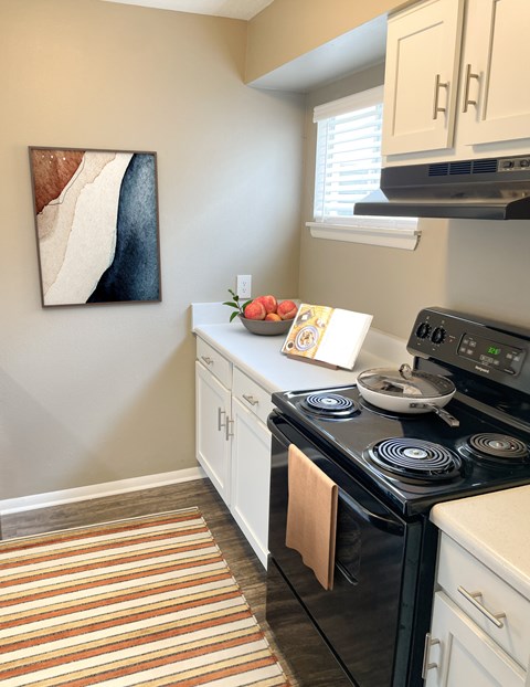A kitchen with a black stove top oven and white cabinets.